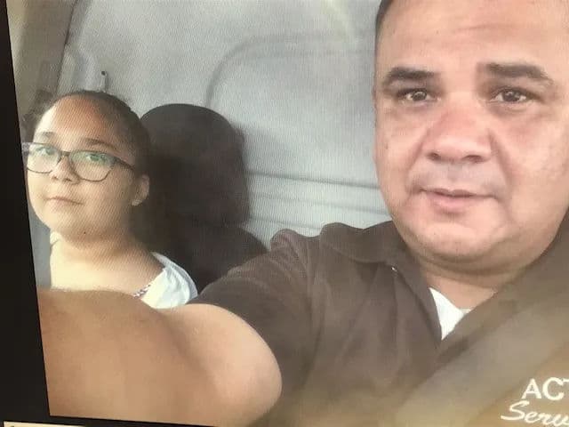 Man and girl taking a selfie in a vehicle, both looking at the camera.
