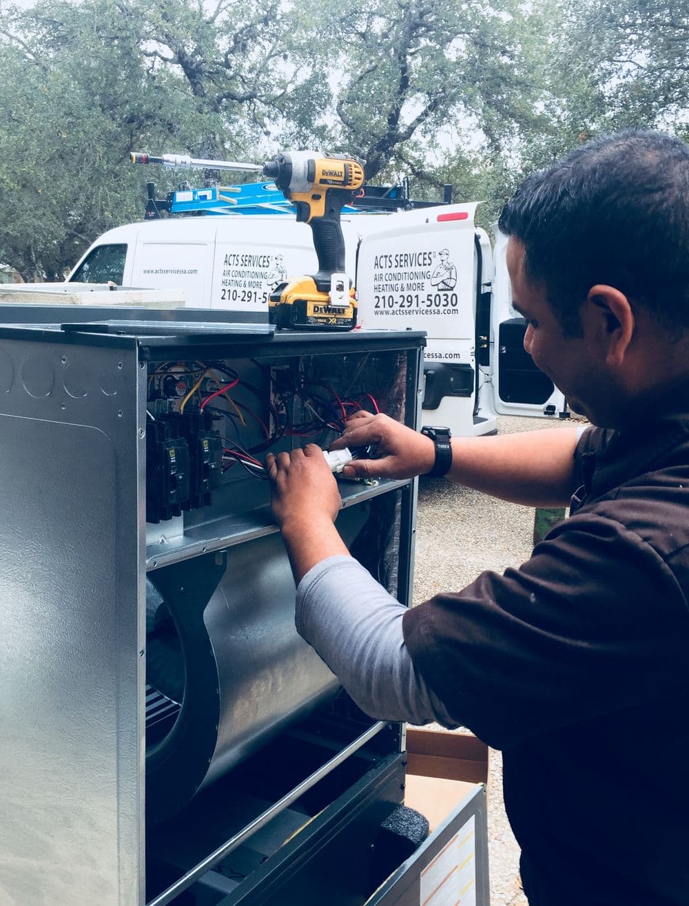 Technician repairing HVAC unit, showcasing electrical components and tools for maintenance.