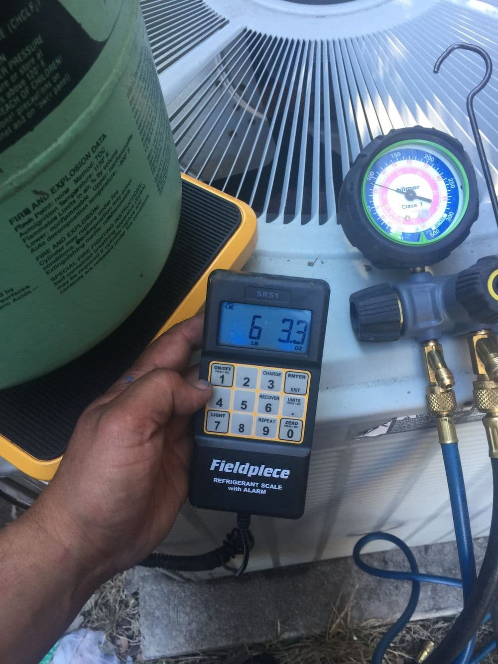 Fieldpiece refrigerant scale displaying 6.3, with AC manifold gauges nearby.